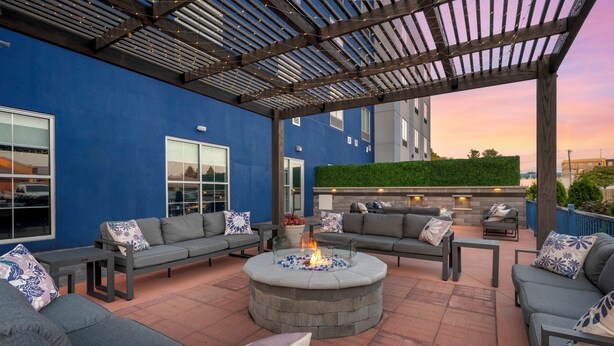 A covered outdoor seating area with a fire pit, sofas, and a pergola. - Comfort Suites Richmond East (Richmond)