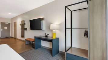 Una habitación de hotel moderna con cama, escritorio con lámpara, televisión y armario.