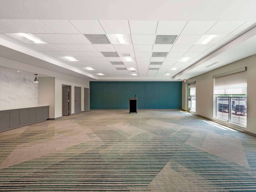 Uma sala de conferências espaçosa com carpete estampado, um púlpito e uma grande janela com vista para o exterior.