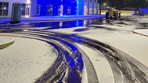 A modern building with a blue-lit facade, a snow-covered ground, and a visible snow-clearing vehicle. - Comfort Suites Richmond East (Richmond)