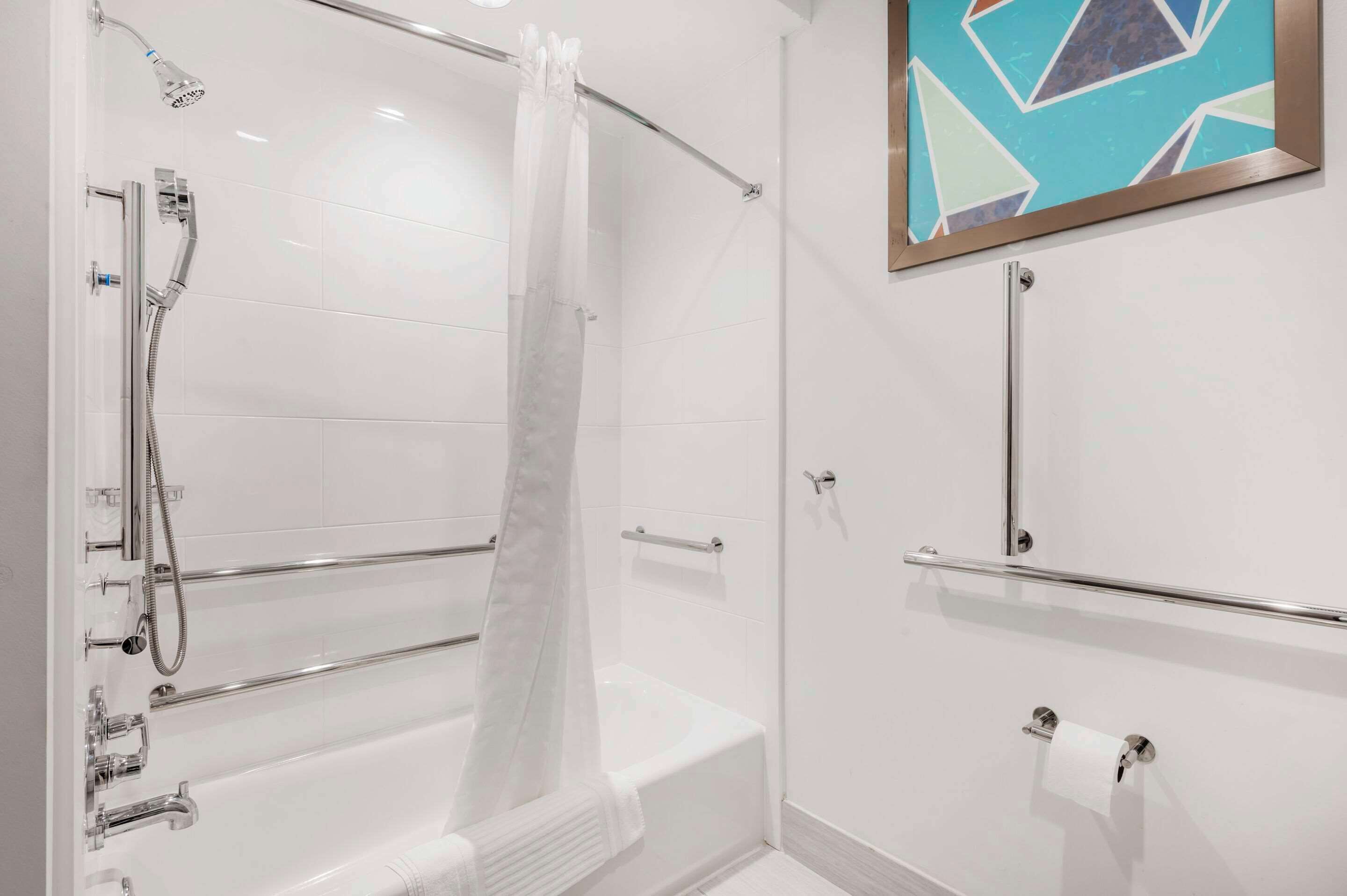 Un baño moderno con cabina de ducha de vidrio, bañera y lavamanos con toallero.