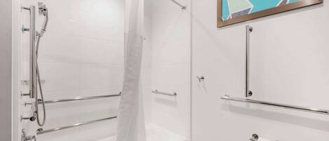 Un baño moderno con cabina de ducha de vidrio, bañera y lavamanos con toallero.
