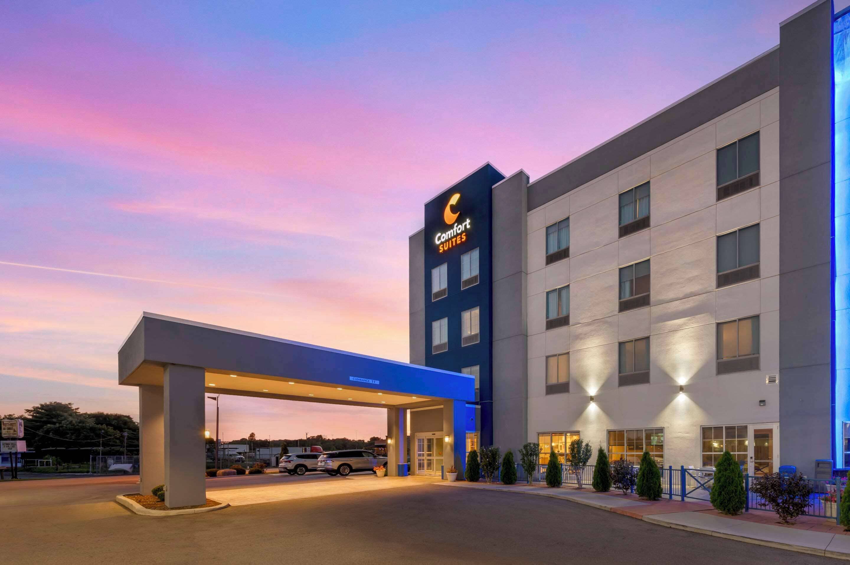 Un hotel de diseño moderno, con un llamativo letrero Comfort Suites y una entrada bien iluminada.