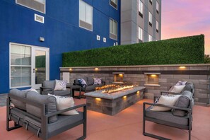 An outdoor seating area with a fire feature, grey sofas, and a green wall. - Comfort Suites Richmond East (Richmond)