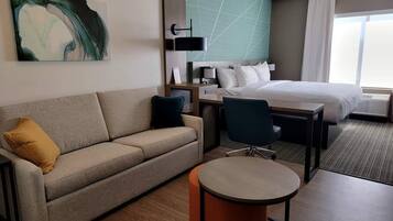 A hotel room with a bed, a sofa, a desk, and a chair.
