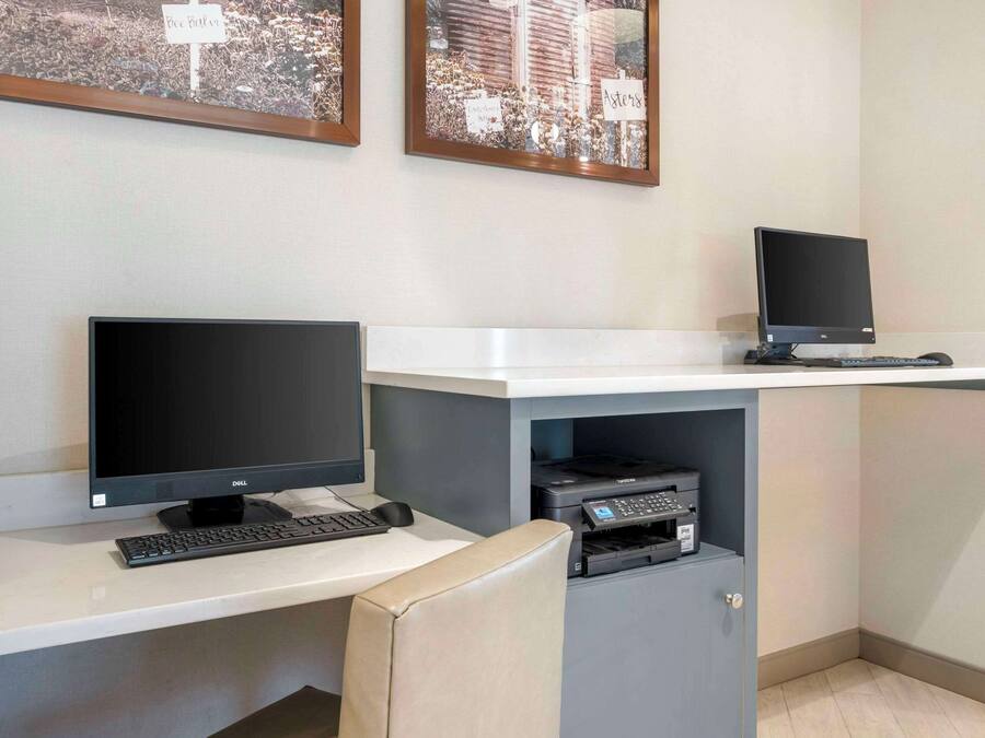 Un espai de treball amb dos monitors, un teclat i una impressora sobre una taula.