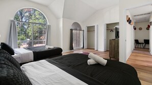 Une chambre d’hôtel moderne avec deux lits, une grande fenêtre, une armoire et une vue sur l’extérieur.
