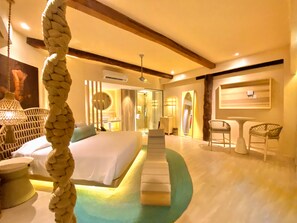A hotel room with a bed, a sitting area with chairs, a small table, and a mirror. - Hotel Shibari Tulum (Tulum)