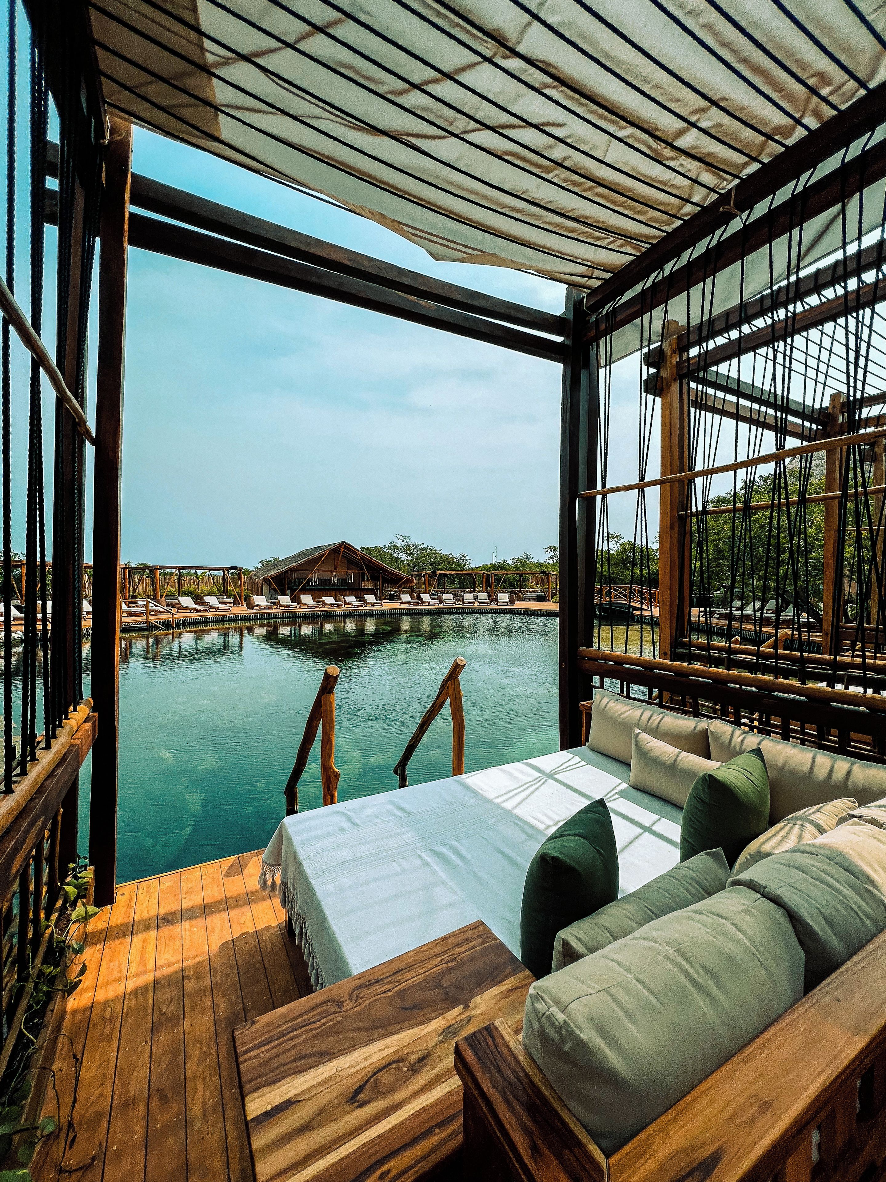 A room with a view of a pool and a wooden deck.