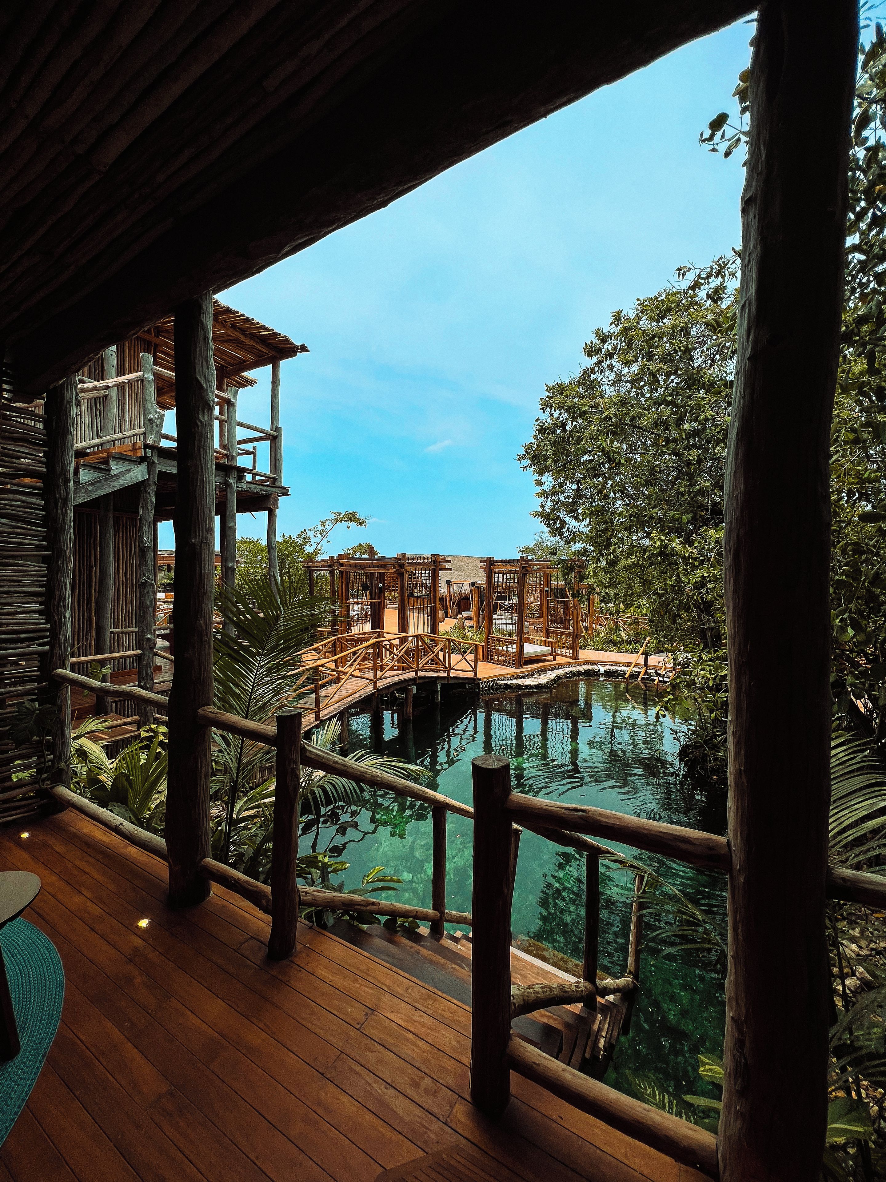 Una terraza de madera con vista a una piscina y un puente.
