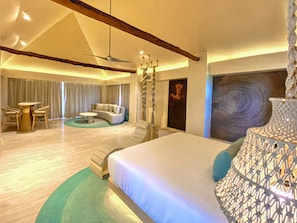 A modern hotel room with a large bed, a seating area with a sofa and chairs, a dining table, and a chandelier. - Hotel Shibari Tulum (Tulum)