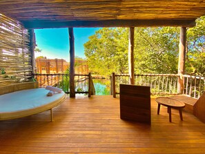 A wooden deck with a hammock, a wooden chair, and a view of a pool and trees. - Hotel Shibari Tulum (Tulum)