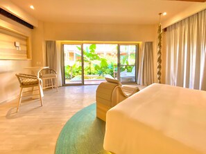 A hotel room with a bed, a chair, a table, and a view of the outdoors through a sliding door. - Hotel Shibari Tulum (Tulum)