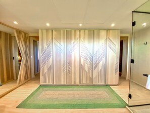 A room with a large sliding door, a green rug, and a glass partition. - Hotel Shibari Tulum (Tulum)