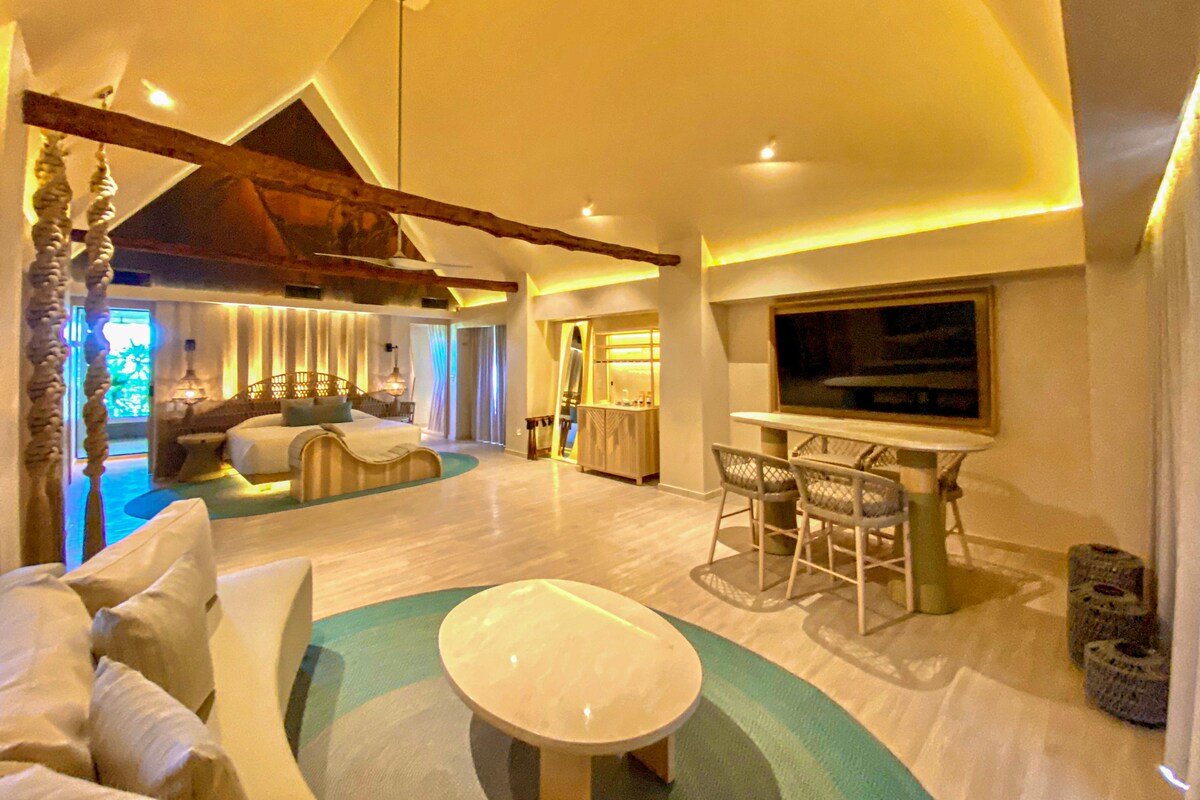 A spacious living area with a large sofa, a dining table with chairs, and a view of the outdoors.