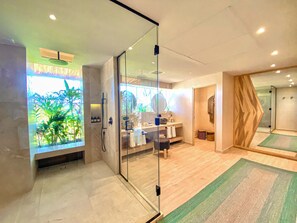 A modern bathroom with a glass shower enclosure, a vanity with a mirror, and a view of greenery outside. - Hotel Shibari Tulum (Tulum)