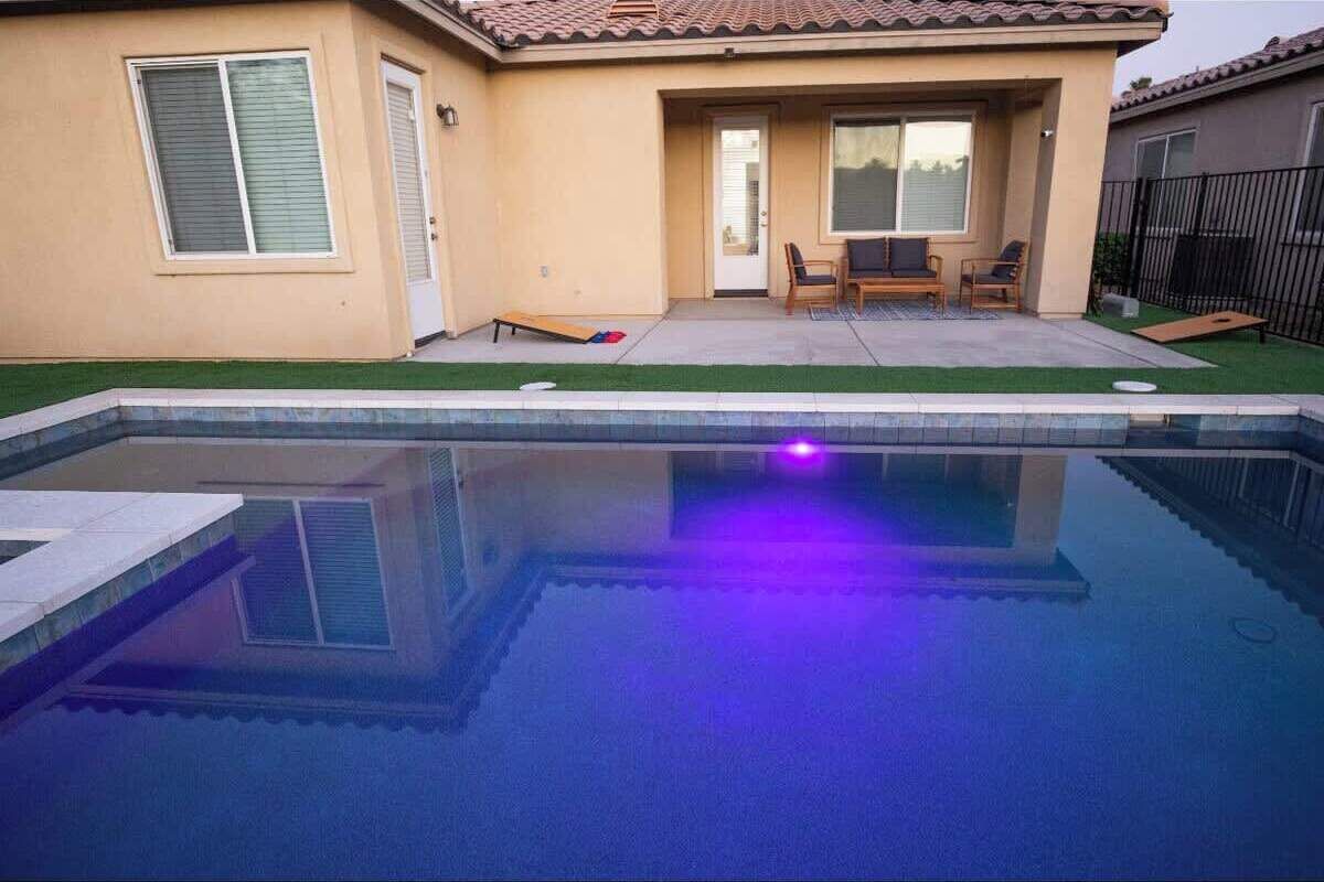 A residential swimming pool with a patio area, a door, and a window.