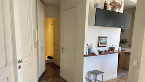 A narrow hallway with a patterned floor leading to a kitchen area with a wooden counter and cabinets. - Nice 56m² with balcony in rotunda near the sea (Nice)