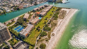 Vista aérea de una zona residencial costera con un puerto deportivo, cancha de tenis y una playa.
