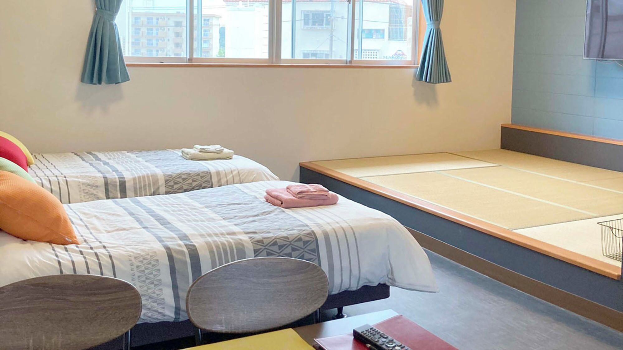 A hotel room with two beds, a small table, and a chair.