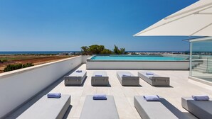 Una terraza en la azotea con tumbonas, piscina y vistas despejadas al mar.