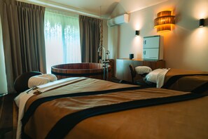 A hotel room with two beds, a wooden bathtub, a desk, and a wall-mounted air conditioner.