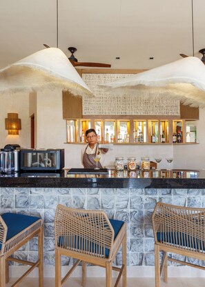 A bar area with a counter, bar stools, and a person serving drinks.