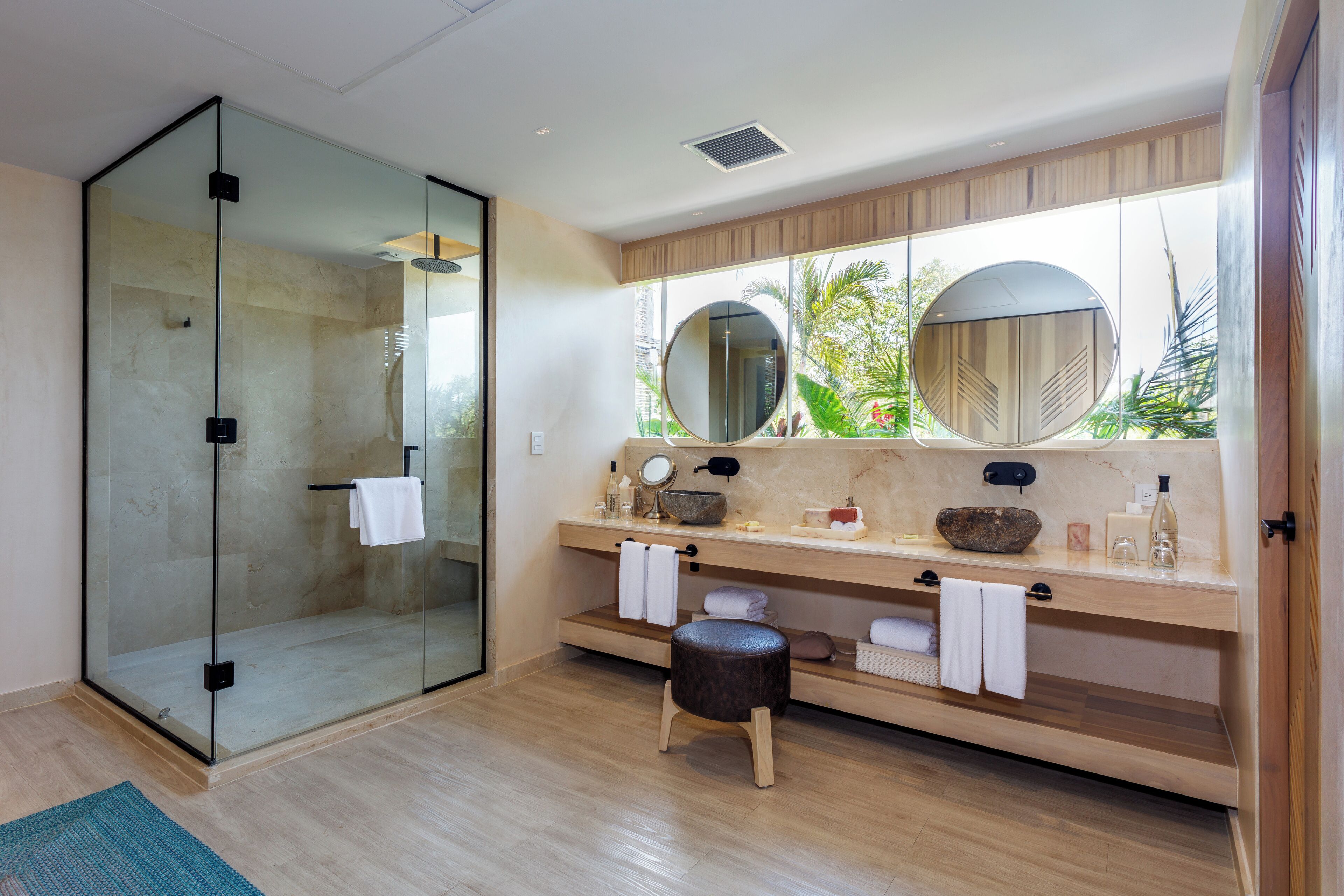 A modern bathroom with a glass shower enclosure, wooden vanity, and a large mirror.