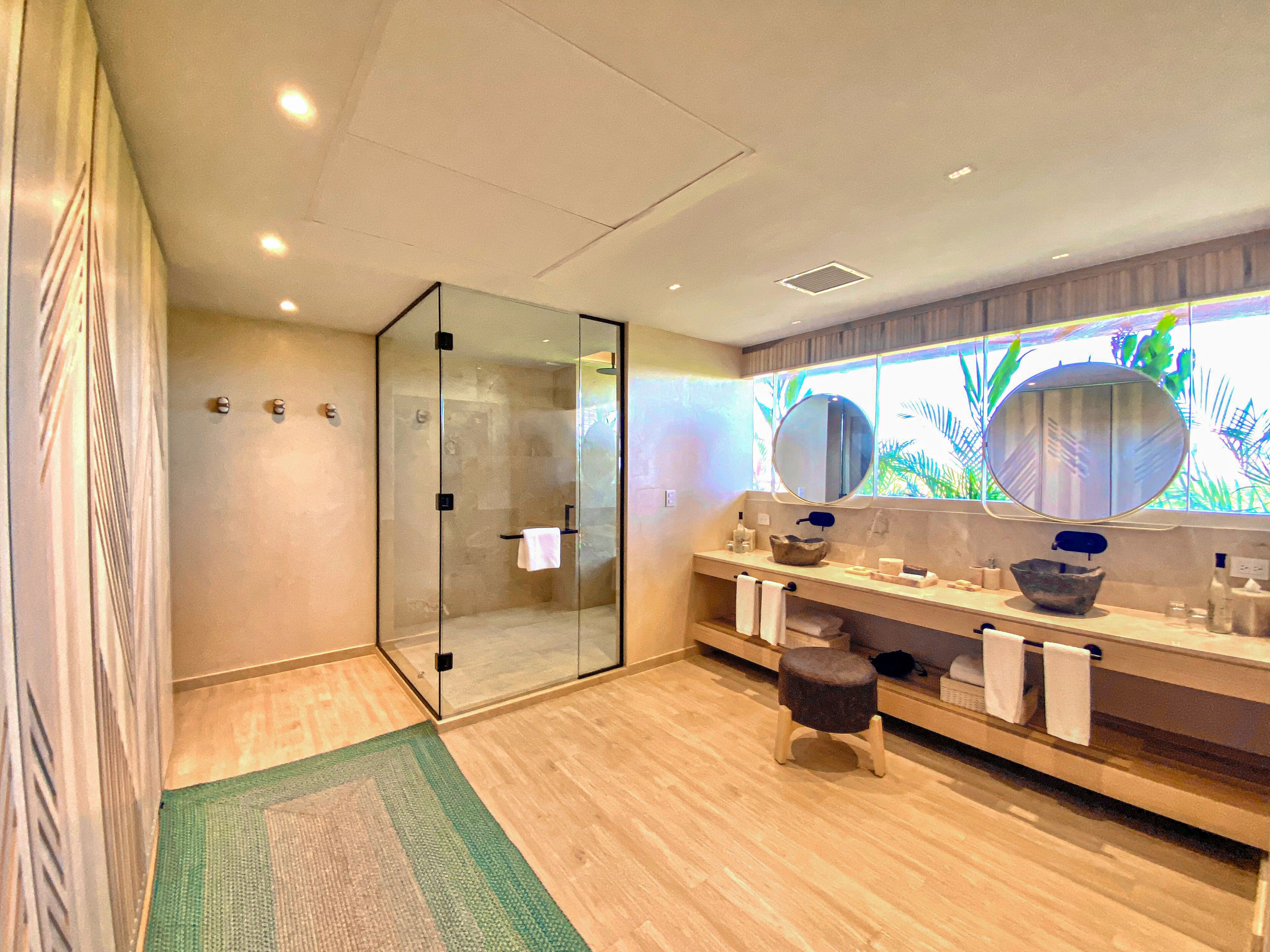 A modern bathroom with a glass shower enclosure, a vanity with dual sinks, and a large mirror above the sink.