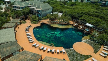 Relax by the central pool surrounded by accommodations with thatched roofs, nestled in lush greenery.