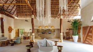 Un hall espacioso con techo alto, muebles de madera y una zona de estar central.