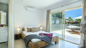 A modern bedroom with a wooden bed, a large window, and a view of the outdoors. - Villa Isabella by Villa Plus (Mallorca)