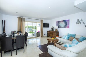 Een ruime woonkamer met een eettafel, bank en een aan de muur bevestigde televisie.