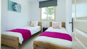 A bedroom with two wooden beds, white bedding, and a window with a dark blind. - Villa Isabella by Villa Plus (Mallorca)