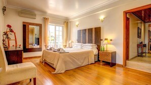 A spacious bedroom with a large bed, bedside tables, a chair, and a mirror. - Villa Daisy by Villa Plus (Lagos)