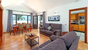 A spacious living area with a dining table, sofas, and a kitchen visible through an open door. - Villa San Marcial by Villa Plus (Tías)