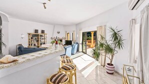 A spacious living area with a sofa, a coffee table, and a TV. There is a bookshelf and a fireplace. - Villa Racanda by Villa Plus (Carvoeiro)