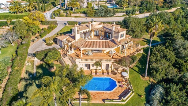 An aerial view of a large, multi-story house with a swimming pool, surrounded by lush greenery and palm trees. - Villa Racanda by Villa Plus (Carvoeiro)