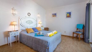 Ein Schlafzimmer mit einem Bett, zwei Nachttischen, einem Sessel und zwei Wandlampen.