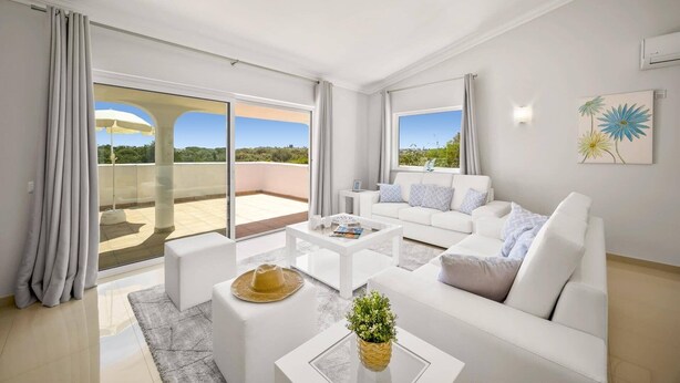 A modern living room with a white sofa, a coffee table, and a balcony with a view. - Villa Citrinos by Villa Plus (Almansil)