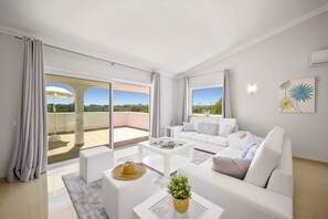 A modern living room with a white sofa, a coffee table, and a balcony with a view.