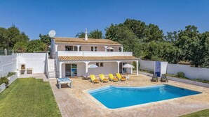 Una casa a due piani con piscina, area salotto esterna e antenna parabolica.