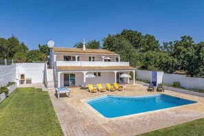 Ein zweistöckiges Haus mit Schwimmbad, Sitzgelegenheiten im Freien und einer Satellitenschüssel.