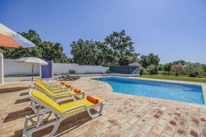 A swimming pool area with lounge chairs and umbrellas.