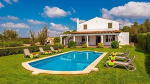 Una villa moderna con piscina, patio coperto e giardino curato.