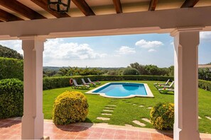 Una piscina con sillas de descanso, una pérgola y vistas al campo.