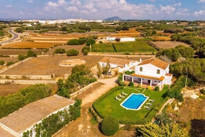 Una villa blanca con piscina, rodeada de céspedes verdes y campos.