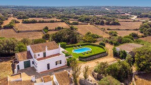 Una villa circondata da campi a terrazza e alberi, con una piscina.