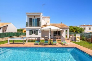 A two-story house with a swimming pool, outdoor furniture, and a satellite dish.