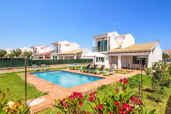 Ein Wohnhaus mit Schwimmbad, überdachter Terrasse und Garten.